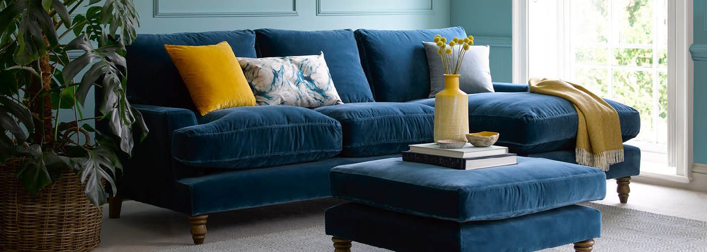 Blue velvet sofa and footstool in furnished living room